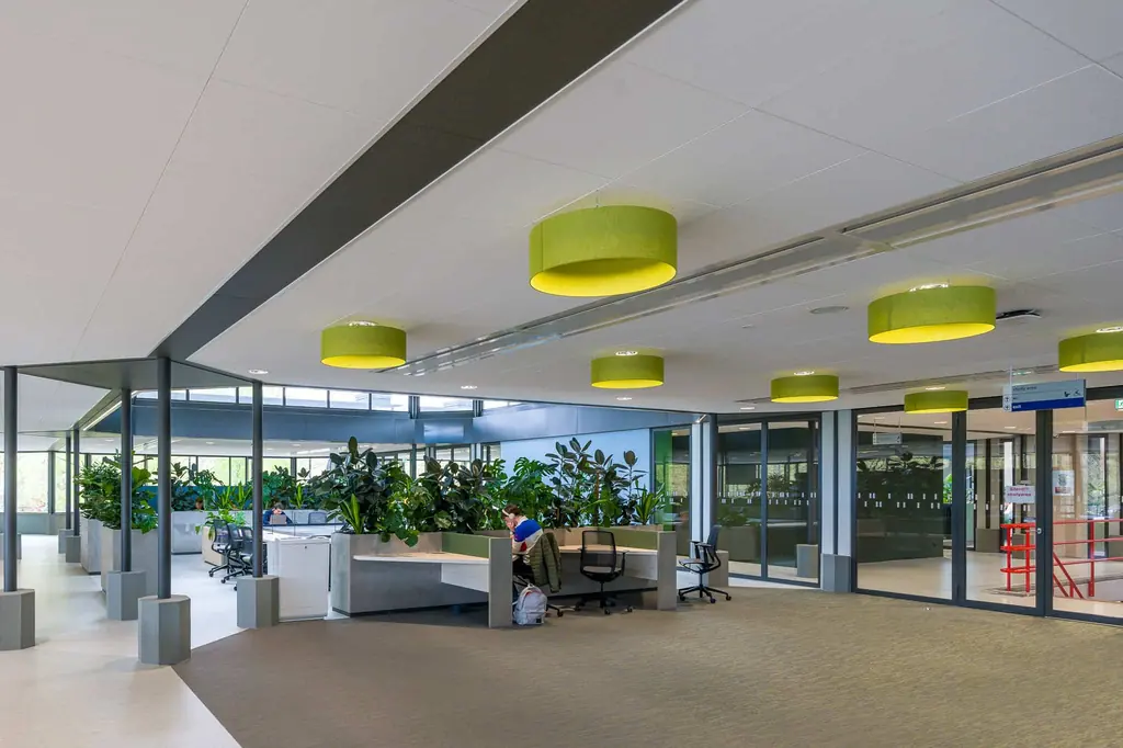 Kantoortuin in gebouw Neuron met systeemplafond en groene hanglampen